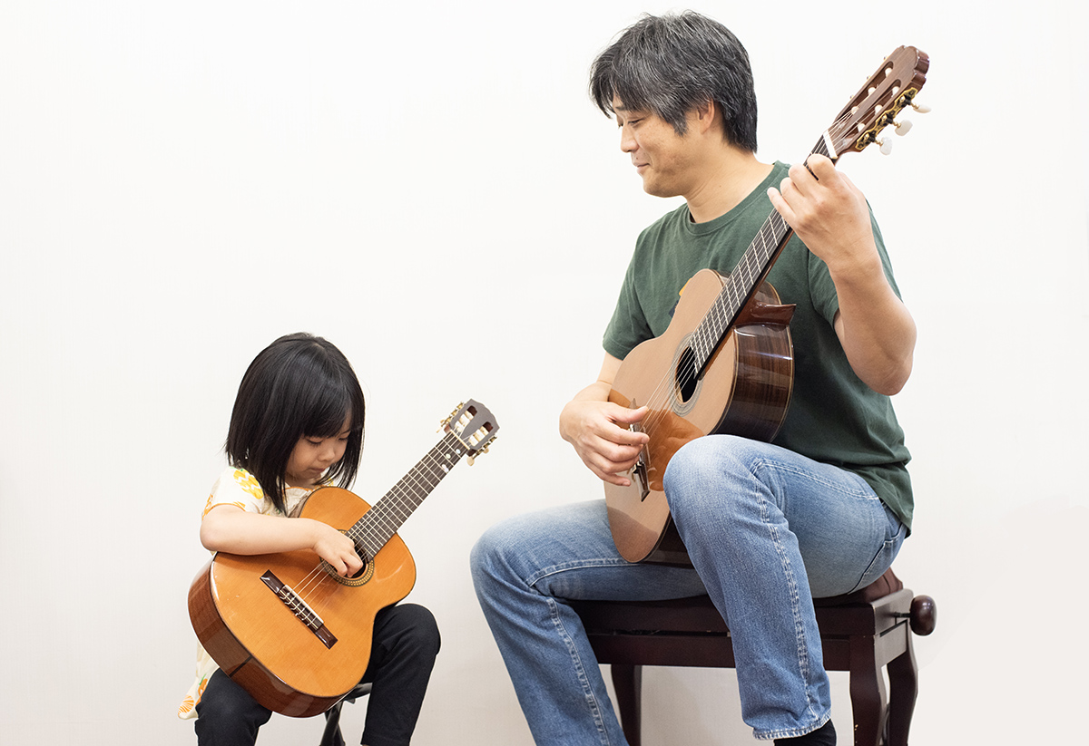講師と一緒にギターを弾く様子
